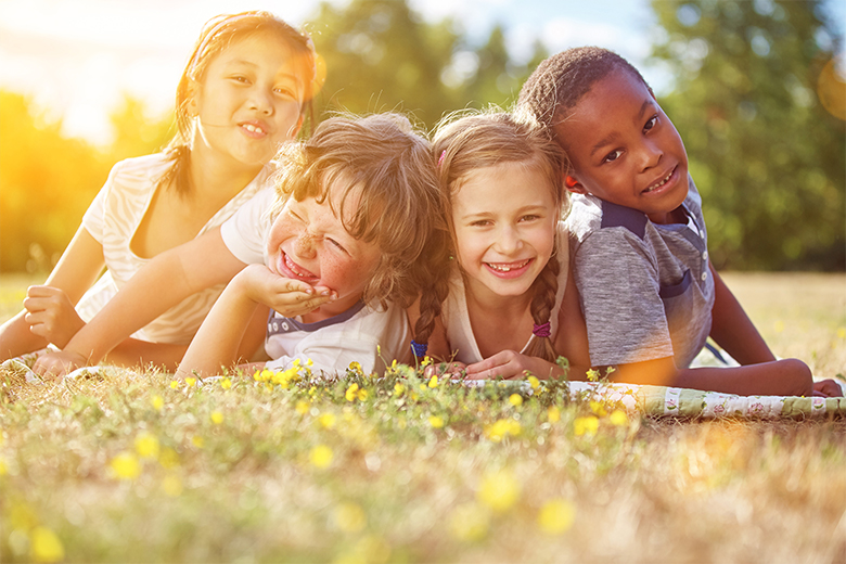 Image of multicultural children smiling in the sun in a field